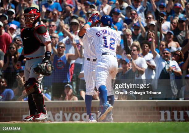 The Chicago Cubs' Kyle Schwarber is high-fived by teammate Addison Russell after he scored on a double by Victor Caratini in the fourth inning at...