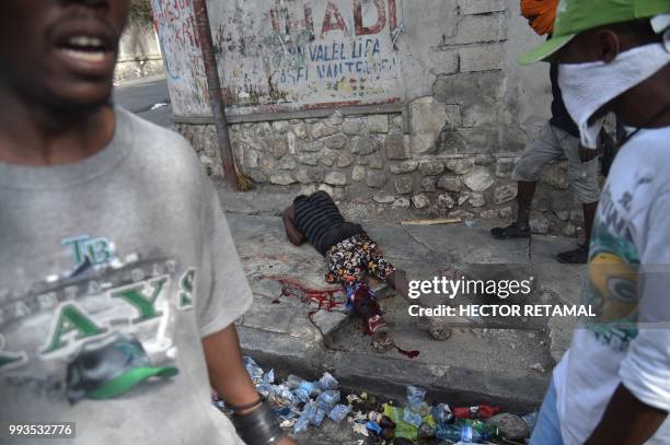 Wounded man lies on a road following clashes with Haitian Police during a protest against the increase in fuel prices, July 7, 2018 in...