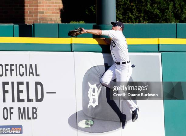 Center fielder JaCoby Jones of the Detroit Tigers reaches over the wall to catch a fly ball hit by Adrian Beltre of the Texas Rangers during the...