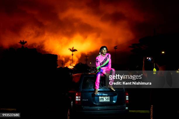Jayden Jennings of West Palm Beach sits on the roof of his families car while posing for a picutre with the glow of Fissure No. 8 in the background,...