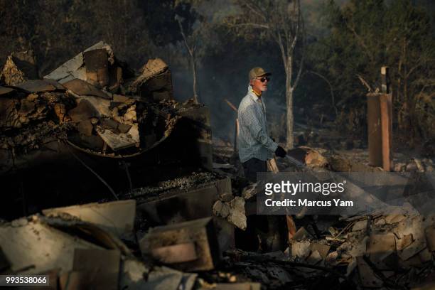 John Givens sorts through the rubble of his home that was destroyed by wildfire in Goleta, Calif., on July 7, 2018.