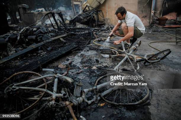 Eric Durtschi searches through the rubble for personal belongings after his home was destroyed by wildfire, in Goleta, Calif., on July 7, 2018.