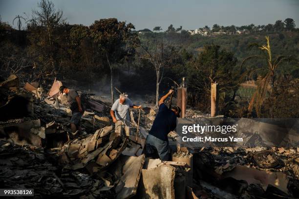 John Givens' neighbors help him dig and salvage through the rubble of his home that was destroyed by wildfire, in Goleta, Calif., on July 7, 2018.