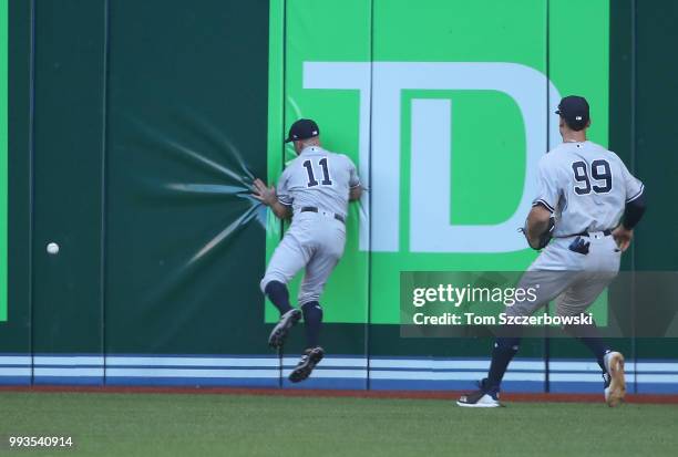 Brett Gardner of the New York Yankees crashes into the outfield wall in pursuit of a double hit by Justin Smoak of the Toronto Blue Jays as Aaron...