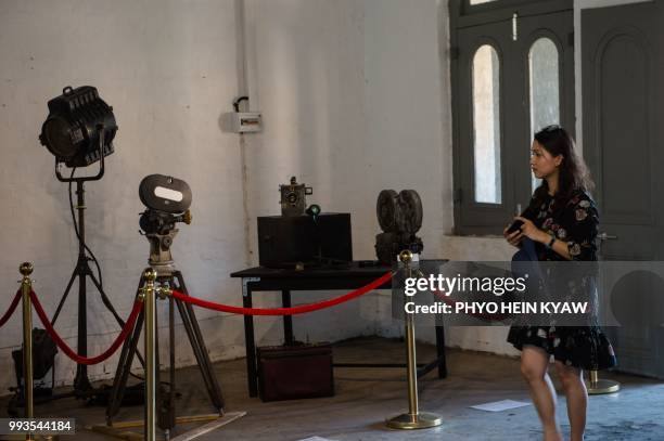 This picture taken on April 12, 2018 shows a visitor views a display of vintage camera and projector at the Myanmar film heritage exhibition at the...