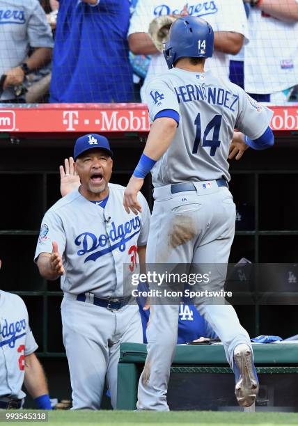 Los Angeles Dodgers manager Dave Roberts greets second baseman Enrique Hernandez at the dugout in the fifth inning after Hernandez scored on a single...