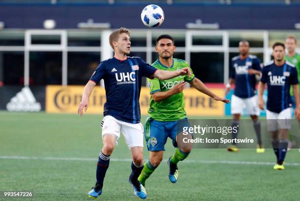 New England Revolution midfielder Scott Caldwell looks to play the ball as Seattle Sounders FC midfielder Cristian Roldan moves in during a match...