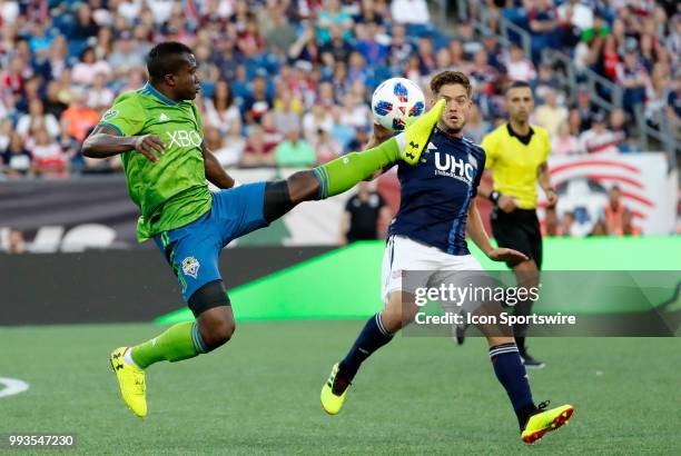 Seattle Sounders FC defender Nouhou Tolo plays the ball in front of New England Revolution midfielder Kelyn Rowe during a match between the New...