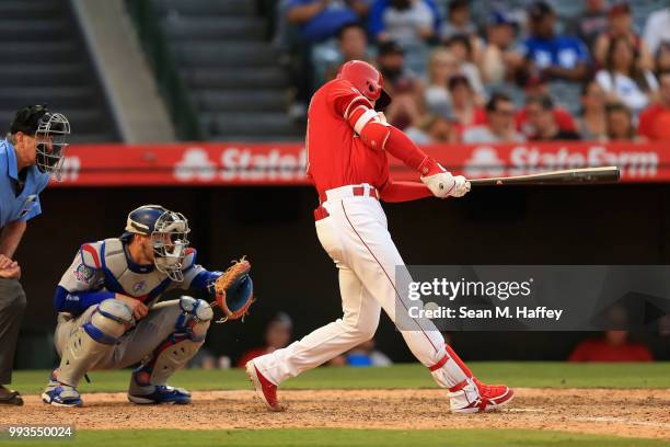 Shohei Ohtani of the Los Angeles Angels of Anaheim fouls a ball off of his knee as Yasmani Grandal of the Los Angeles Dodgers and umpire Mike Winters...