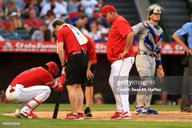 Manager Mike Scioscia looks on as Shohei Ohtani of the Los Angeles Angels of Anaheim grimaces in pain after hitting a foul off his knee while Yasmani...