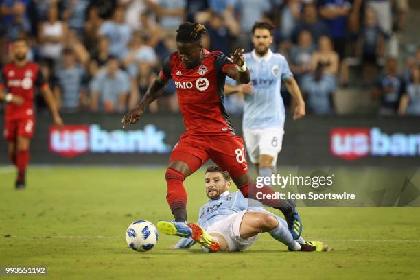 Sporting Kansas City midfielder Ilie Sanchez goes under Toronto FC forward Tosaint Ricketts for a slide tackle in the second half of an MLS match...