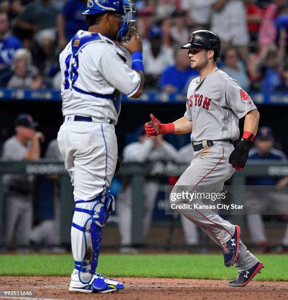 The Boston Red Sox's Andrew Benintendi, right, scores in front of Kansas City Royals catcher Salvador Perez on a sacrifice fly by Mitch Moreland in...