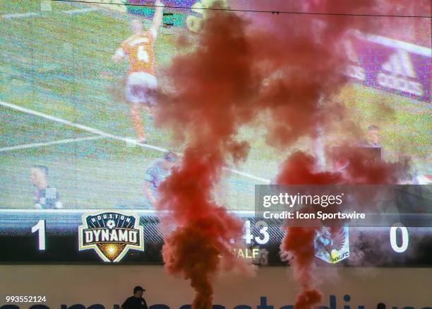 Houston Dynamo fan watches orange plumes of smoke go up in celebration of a goal scored during the soccer match between the Minnesota United FC and...