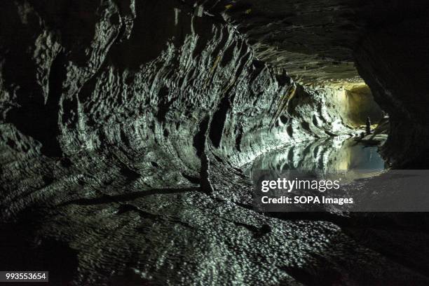 Tunnel with some water inside the cave. Ingleborough Cave is a beautiful cave close to the village of Clapham in North Yorkshire, England adjacent to...