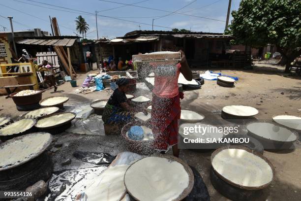 Women sieve cassava for the preparation of the attieke side dish in Abidjan, on May 22, 2018. - Researchers from half a dozen states in West Africa...