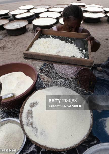 Woman sieves semolina of cassava for the attieke side dish in Abidjan, on May 22, 2018. - Researchers from half a dozen states in West Africa have...