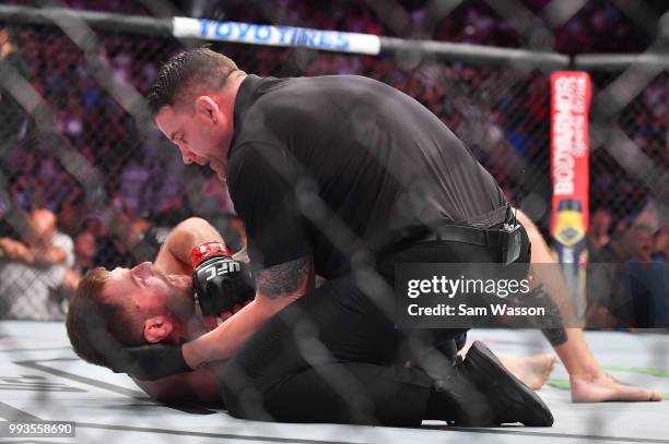 Referee Marc Goddard checks on Stipe Miocic after he was knocked out by Daniel Cormier in the first round of their heavyweight championship fight at...