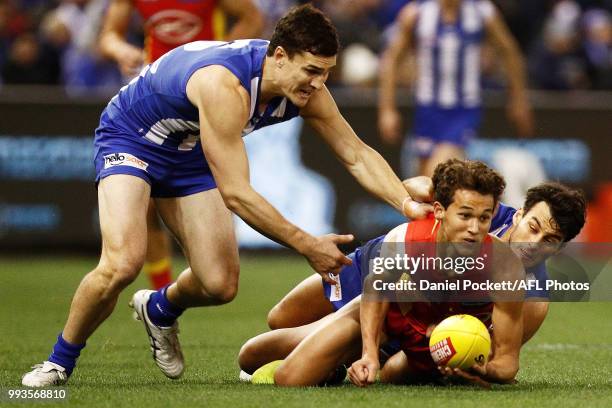 Wil Powell of the Suns handpasses whilst being tackledduring the round 16 AFL match between the North Melbourne Kangaroos and the Gold Coast Titans...