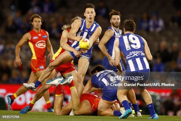 Jy Simpkin of the Kangaroos handpasses the ball whilst being tackled during the round 16 AFL match between the North Melbourne Kangaroos and the Gold...