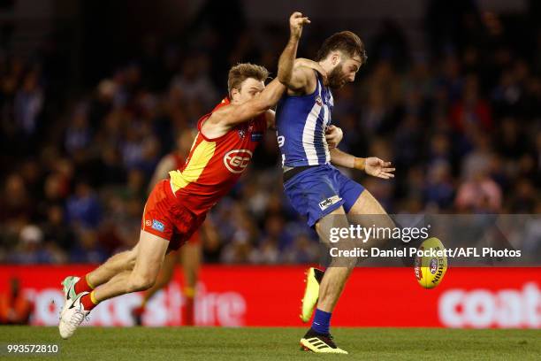 Luke McDonald of the Kangaroos kicks the ball whilst being tackled during the round 16 AFL match between the North Melbourne Kangaroos and the Gold...