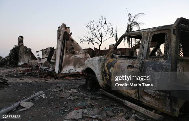 The charred remains of a destroyed vehicle and home stand in the aftermath of the Holiday Fire on July 7, 2018 in Goleta, California. The fire...