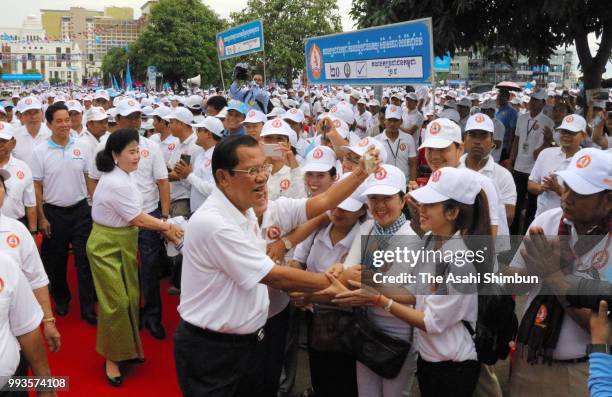 Prime Minister and President of ruling Cambodian People's Party Hun Sen shakes hands with party supporters prior to a campaign rally as the general...