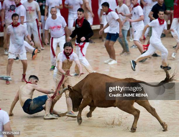 Reveller is tossed by a heifer bull during festivities in the bullring on the second bull run of the San Fermin festival in Pamplona, northern Spain...