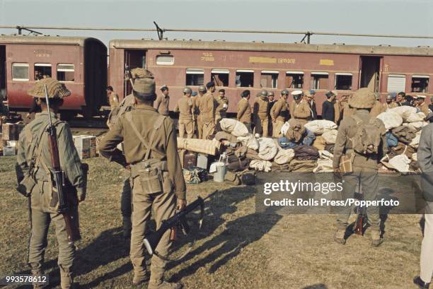 Supervised by armed Indian troops, defeated Pakistan Army soldiers prepare to board a train in Dhaka , East Pakistan for the first stage of their...