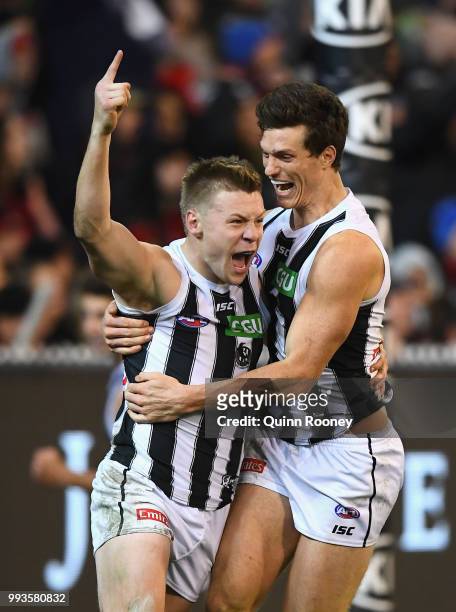 Jordan De Goey of the Magpies is congratulated by Brody Mihocek after kicking a goal during the round 16 AFL match between the Essendon Bombers and...