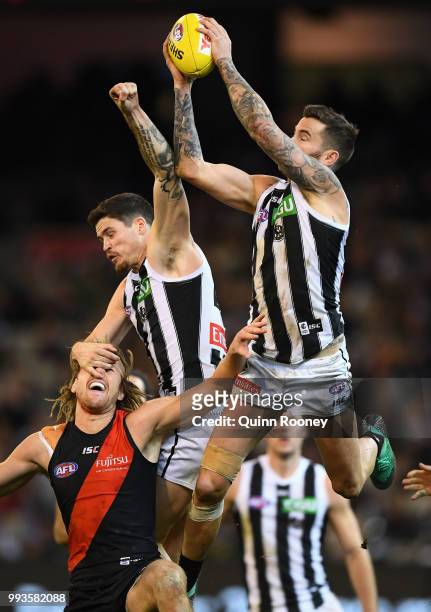 Jeremy Howe of the Magpies marks over the top of Dyson Heppell of the Bombers during the round 16 AFL match between the Essendon Bombers and the...