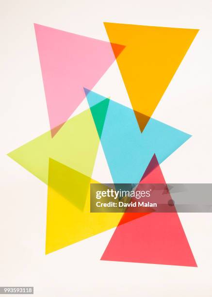 overlapping multicoloured paper triangles on a lightbox. - malan stock pictures, royalty-free photos & images