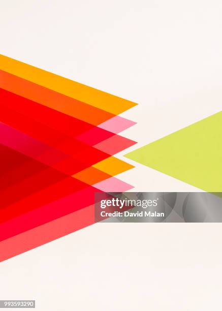 one green triangle opposing many red, pink and orange triangles. - malan stock-fotos und bilder