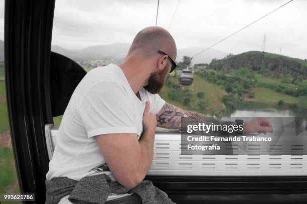 tattooed man traveling by cable car - fernando trabanco ストックフォトと画像