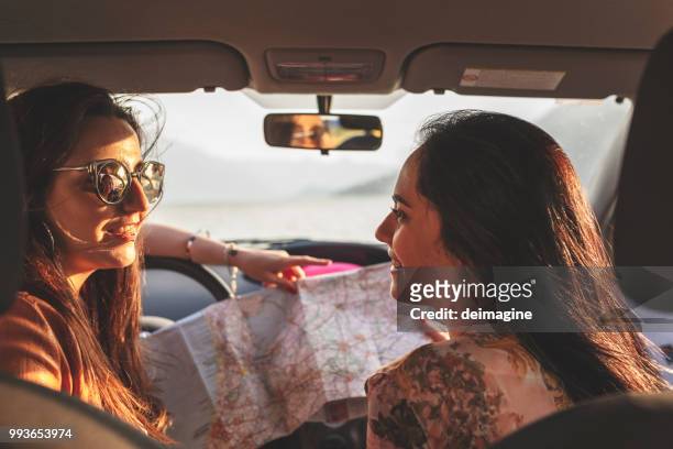 happy women couple with road map in the car - car ferry stock pictures, royalty-free photos & images