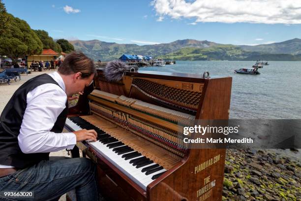 the travelling pianist at work on akaroa harbour waterfront - akaroa stock-fotos und bilder