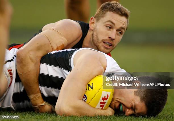 Jack Crisp of the Magpies is tackled by Devon Smith of the Bombers during the 2018 AFL round 16 match between the Essendon Bombers and the...