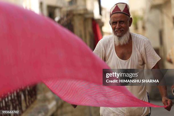 An Indian man dries a turban after being colored in Ajmer, in the Indian state of Rajasthan, on July 08, 2018.