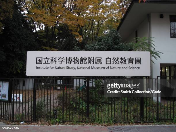 Sign on a metal fence, lettering "Institute For Nature Study, National Museum of Nature and Science", Shirokane, Tokyo, Japan, November 28, 2017.