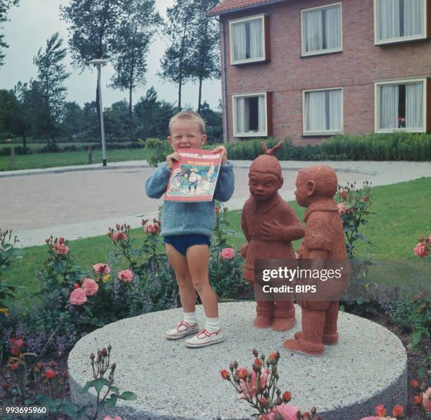 Boy standing near statues of 'Suske en Wiske', also known as 'Spike and Suzy', main characters in the Belgian comics series created by comics author...