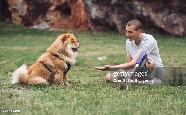 disability man and dog relaxing - white chow chow stock pictures, royalty-free photos & images
