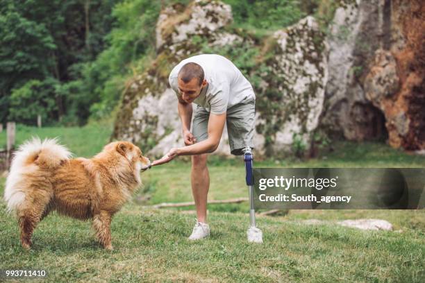 disability guy playing with chow dog - white chow chow stock pictures, royalty-free photos & images