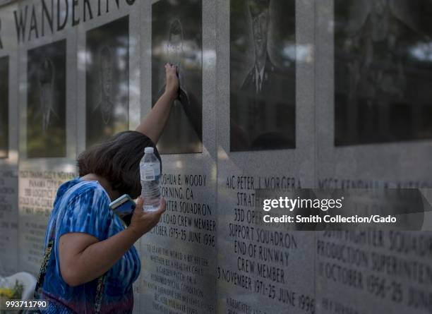 Family member of a 33rd Fighter Wing Khobar Towers victim places her hand on his photo June 25 at Eglin Air Force Base, Fla. Each year, past and...