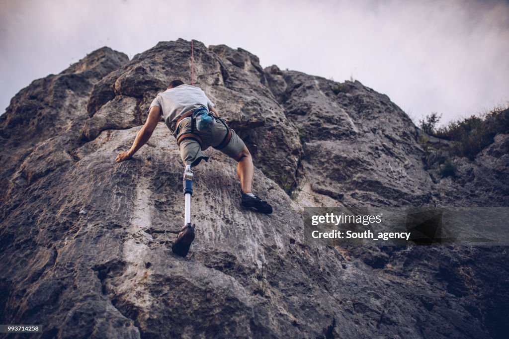Disability man climbing rocks