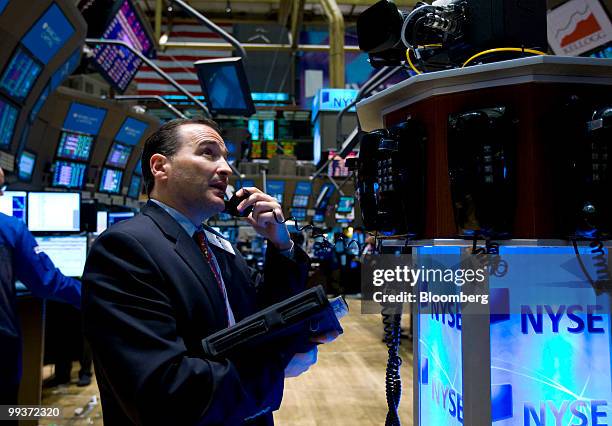 Trader looks up at a monitor while talking on the phone from the floor of the New York Stock Exchange in New York, U.S., on Friday, May 14, 2010....