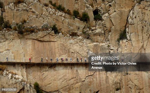 line of hikers along the caminito del rey walkway hanging from the cliffs of el chorro gorge above guadalhorce river - caminito del rey málaga province stock pictures, royalty-free photos & images
