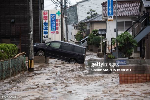 Picture shows cars trapped in the mud after floods in Saka, Hiroshima prefecture on July 8, 2018. - Japan's Prime Minister Shinzo Abe warned on July...
