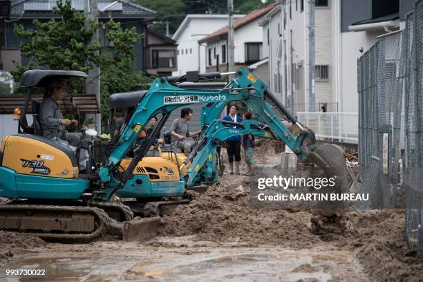 People use escavators to remove the mud after floods in Saka, Hiroshima prefecture on July 8, 2018. - Japan's Prime Minister Shinzo Abe warned on...