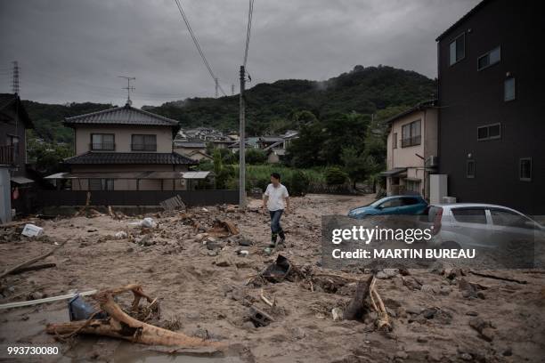 Man walks past a devastated street during floods in Saka, Hiroshima prefecture on July 8, 2018. - Japan's Prime Minister Shinzo Abe warned on July 8...