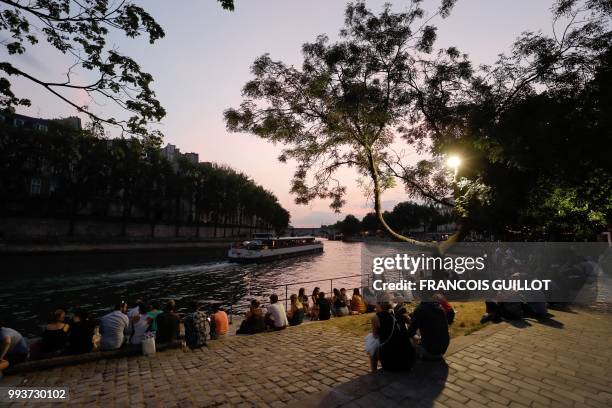 People sit on the banks of the Seine on July 7, 2018 in Paris as part of the Paris Plages summer event.