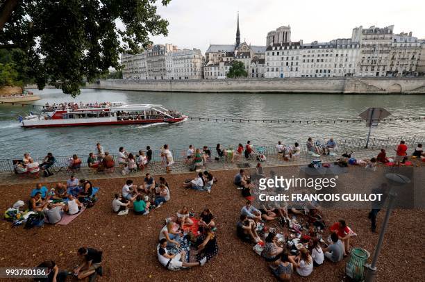 People sit on the banks of the Seine on July 7, 2018 in Paris as part of the Paris Plages summer event.